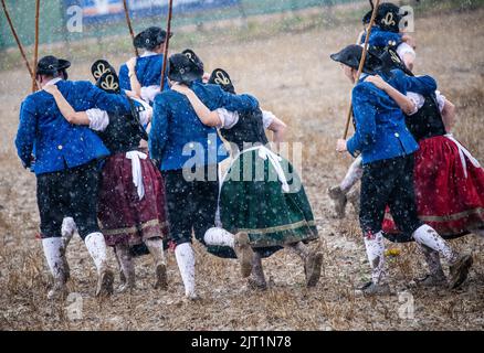 27. August 2022, Baden-Württemberg, Markgröningen: Bei starkem Regen führen die Teilnehmer des Markgröninger Schäferlaufs den Schäfer-Tanz auf einem Stoppelfeld auf. Foto: Christoph Schmidt/dpa Stockfoto