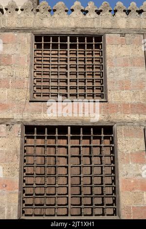 Alte islamische Steinmauer mit traditionellen Holz- und Stahlstangen-Fenstern Stockfoto