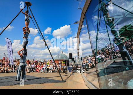 London, Großbritannien. 27. August 2022. Sisyphus treten auf der spektakulären Outdoor-Bühne vor der Cutty Sark beim Greenwich and Docklands International Festival auf. Drei unglaubliche Zirkuskünstler kombinieren ihre Fähigkeiten im Fliegen, Partnerakrobatik und Gurte, um die pure Freude zu feiern, die ihr Publikum heute bei schönem Sonnenschein fesselt. Kredit: Imageplotter/Alamy Live Nachrichten Stockfoto