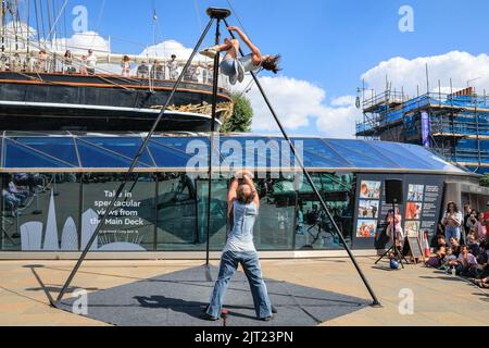 London, Großbritannien. 27. August 2022. Sisyphus treten auf der spektakulären Outdoor-Bühne vor der Cutty Sark beim Greenwich and Docklands International Festival auf. Drei unglaubliche Zirkuskünstler kombinieren ihre Fähigkeiten im Fliegen, Partnerakrobatik und Gurte, um die pure Freude zu feiern, die ihr Publikum heute bei schönem Sonnenschein fesselt. Kredit: Imageplotter/Alamy Live Nachrichten Stockfoto