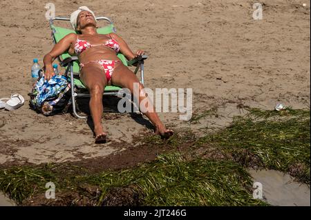 Alicante, Spanien. 27. August 2022. Eine Frau, die an einem heißen Sommertag am Strand von El Postiguet sonnenbaden geht. Das gesamte touristische Angebot in der Provinz Alicante hat die Belegungsdaten vor der Pandemie wiederhergestellt, wobei Touristenwohnungen und Hotels während eines Teils des Sommers eine Belegung von fast 100 % verzeichnen. Quelle: Marcos del Mazo/Alamy Live News Stockfoto