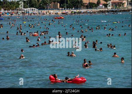 Alicante, Spanien. 27. August 2022. Der Strand El Postiguet ist an einem heißen Sommertag überfüllt, während viele Touristen und Einheimische sich sonnen und abkühlen. Das gesamte touristische Angebot in der Provinz Alicante hat die Belegungsdaten vor der Pandemie wiederhergestellt, wobei Touristenwohnungen und Hotels während eines Teils des Sommers eine Belegung von fast 100 % verzeichnen. Quelle: Marcos del Mazo/Alamy Live News Stockfoto