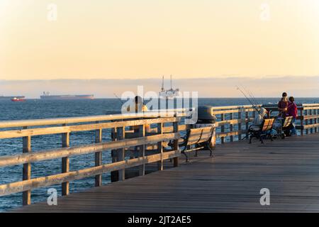 Eine Familie Angeln am Seal Beach Pier bei Sonnenuntergang Stockfoto