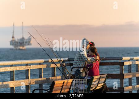 Eine Familie, die am Pier bei Sonnenuntergang angeln kann Stockfoto