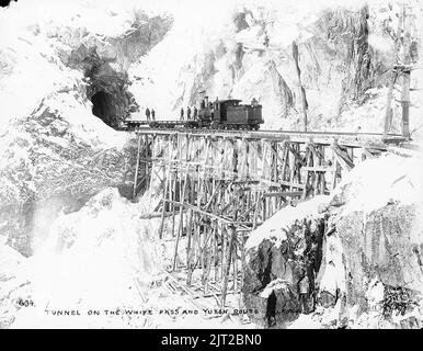 Zug der White Pass & Yukon Railroad auf einer Schotterbrücke, die zum Tunnel zwischen Heney Station und White Pass Summit führt Stockfoto