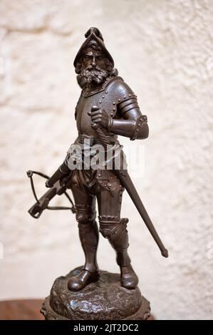 Eine vertikale Nahaufnahme einer alten Bronzestatuette eines Kriegersoldaten mit Rüstung, Schwert und Armbrust Stockfoto