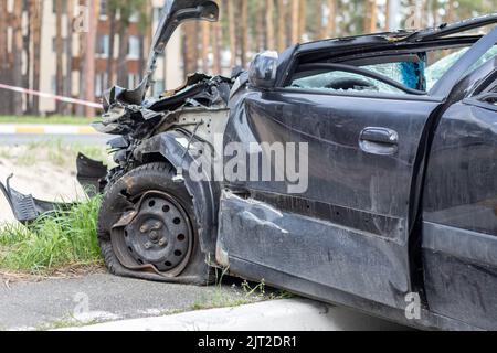 Schwarzes Auto nach einem schrecklichen Unfall am Straßenrand. Frontal- und Seitenaufprall. Lebensversicherung. Ein Unfall ohne die Möglichkeit der Genesung Stockfoto