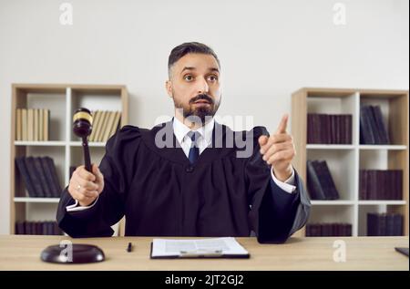 Porträt eines strengen Richters, der auf den Gavel des Richters klopft, verabschiedet das Urteil und erklärt den Fall für geschlossen. Stockfoto