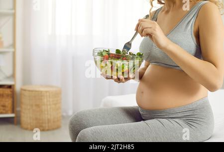 Die junge werdende Mutter kümmert sich um ihre Gesundheit und isst viel frisches Gemüse Stockfoto