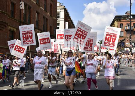 Manchester, Großbritannien. 27.. August 2022. Freiwillige des George House Trust (GHT) tragen U=U- und HIV-bezogene Plakate. GHT sagt: „Seit 1985 inspiriert der George House Trust Menschen, die mit HIV leben, ein gesundes, selbstbewusstes Leben, indem er HIV-Unterstützung, Beratung und Interessenvertretung anbietet.“ Die Teilnehmer nehmen an der LGBTQ+ Pride Parade im Zentrum von Manchester, Großbritannien, Teil, da LGBTQ+ Pride vom 26.. Bis 29.. August am Wochenende der Bankfeiertage fortgesetzt wird. Quelle: Terry Waller/Alamy Live News Stockfoto