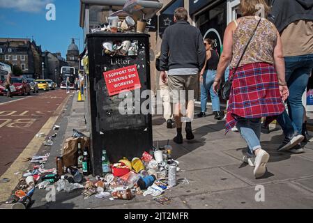 Fußgänger, die an einem überfüllten Abfalleimer in der Nicolson Street aufgrund von Arbeitskampfmaßnahmen der stadtratsmitarbeiter von Edinburgh vorbeilaufen. Stockfoto