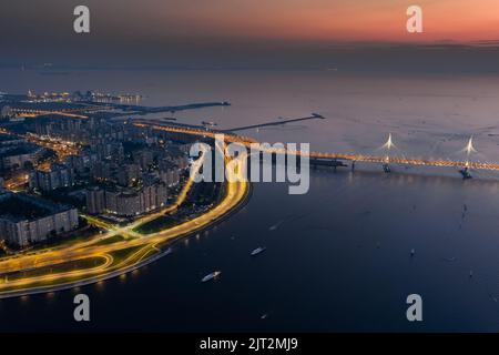 Ein malerischer Sonnenuntergang über der Kabelbrücke und der Vasilevsky-Insel, dem Passagierhafen und der beleuchteten Autobahn Stockfoto