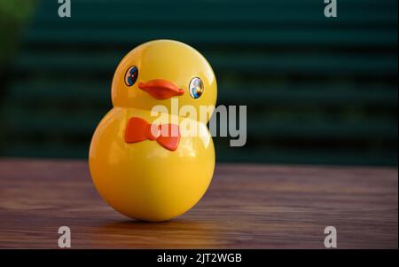 Vintage-Roly-Poly-Spielzeug in der Form eines niedlichen gelben Kükens. Tumbler Spielzeug isoliert auf einem Holztisch im Freien bei Sonnenuntergang. Stockfoto