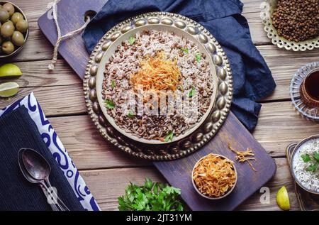 Arabische Küche; traditionelles orientalisches Gericht „Mujadara“ oder „Mudardardara“. Es besteht aus gekochten schwarzen Linsen, Reis und knusprig gebratenen Zwiebeln. Stockfoto