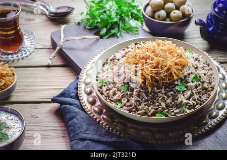 Arabische Küche; traditionelles orientalisches Gericht „Mujadara“ oder „Mudardardara“. Es besteht aus gekochten schwarzen Linsen, Reis und knusprig gebratenen Zwiebeln. Stockfoto