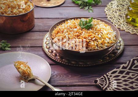 Arabische Küche; ägyptisches orientalisches Gericht „Reis mit Vermicelli“ auf rustikalem Holzhintergrund. Stockfoto