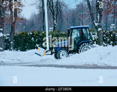 Dnepropetrovsk, Ukraine - 12.30.2021: Blauer Traktor reinigt Stadtstraßen und Straßen nach starkem Schneefall. Kommunale Dienste sind an der Schneeräumung beteiligt Stockfoto