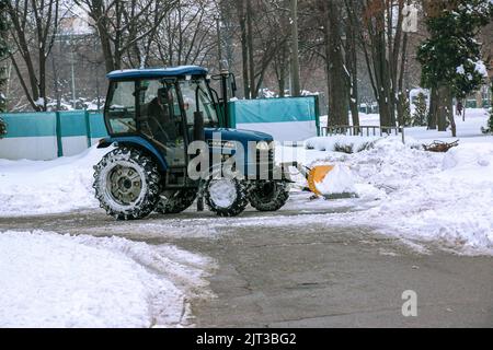 Dnepropetrovsk, Ukraine - 12.30.2021: Blauer Traktor reinigt Stadtstraßen und Straßen nach starkem Schneefall. Kommunale Dienste sind an der Schneeräumung beteiligt Stockfoto