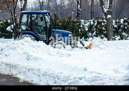 Dnepropetrovsk, Ukraine - 12.30.2021: Blauer Traktor reinigt Stadtstraßen und Straßen nach starkem Schneefall. Kommunale Dienste sind an der Schneeräumung beteiligt Stockfoto