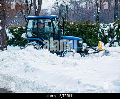 Dnepropetrovsk, Ukraine - 12.30.2021: Blauer Traktor reinigt Stadtstraßen und Straßen nach starkem Schneefall. Kommunale Dienste sind an der Schneeräumung beteiligt Stockfoto