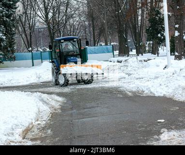 Dnepropetrovsk, Ukraine - 12.30.2021: Blauer Traktor reinigt Stadtstraßen und Straßen nach starkem Schneefall. Kommunale Dienste sind an der Schneeräumung beteiligt Stockfoto