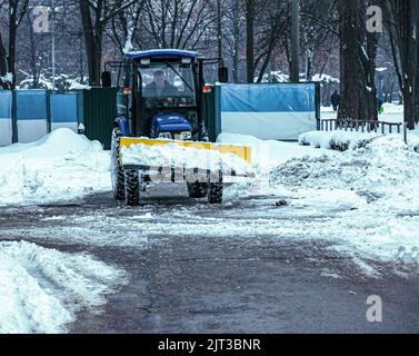 Dnepropetrovsk, Ukraine - 12.30.2021: Blauer Traktor reinigt Stadtstraßen und Straßen nach starkem Schneefall. Kommunale Dienste sind an der Schneeräumung beteiligt Stockfoto