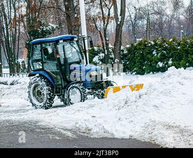 Dnepropetrovsk, Ukraine - 12.30.2021: Blauer Traktor reinigt Stadtstraßen und Straßen nach starkem Schneefall. Kommunale Dienste sind an der Schneeräumung beteiligt Stockfoto