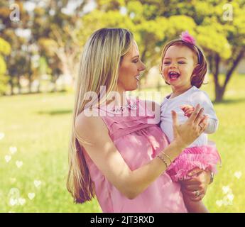 Kannst du dieses kleine und niedliche für immer bleiben. Eine Mutter hält ihr entzückendes kleines Mädchen, während sie draußen steht. Stockfoto