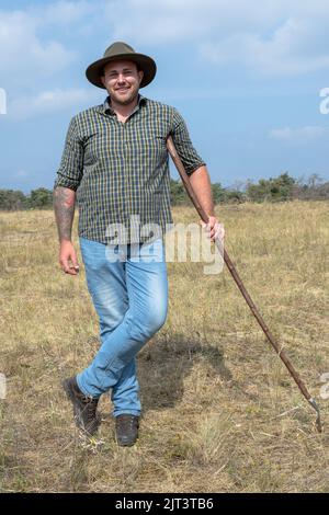 Mainz, Deutschland. 19. August 2022. Der Wanderhirte Finn-Ole Stephan steht auf einem Gebiet im Naturschutzgebiet Mainzer Sand. Zusammen mit einem Eselpfleger ist er an einem Weideprojekt beteiligt, das die Landschaft offen hält und so den Erhalt seltener Pflanzenarten in diesem Steppengrasbiotop ermöglicht. (To dpa: 'Schafe und Esel als Naturschützer - Tierhalter brauchen Unterstützung') Quelle: Peter Zschunke/dpa/Alamy Live News Stockfoto