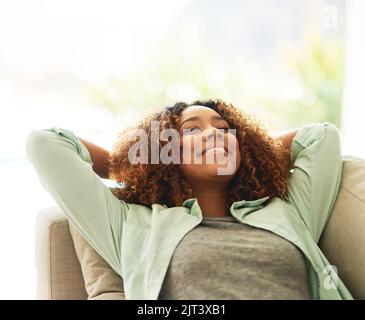 Ein Nickerchen ist das Beste an ihrem Wochenende. Eine attraktive junge Frau, die sich zu Hause auf ihrem Sofa ausruht. Stockfoto