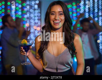 Sie spielen immer alle meine Lieblingslieder in diesem Club. Porträt einer attraktiven jungen Frau, die während einer Party in einem Club einen Drink zu sich nehmen kann. Stockfoto