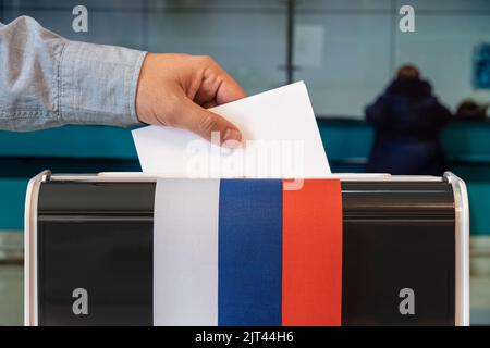 Mann Putting Wahlbilluten in einem Kasten während der Wahlen in russland. russland Flagge. Wähler an einem einzigen Wahltag in Russland in einem Wahllokal wählen Stockfoto