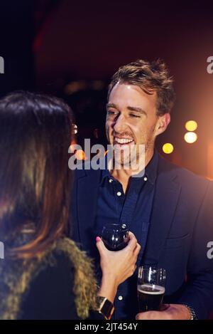 Wie kommt es, dass ich Sie hier noch nie gesehen habe? Zwei Leute plaudern, während sie auf dem Balkon eines Nachtclubs stehen. Stockfoto