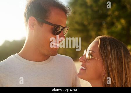 In ihren Augen verloren. Ein liebevolles junges Paar am Strand bei Sonnenuntergang. Stockfoto