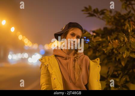 Eine Frau steht in der Nachtstadt im Licht der Laternen Stockfoto