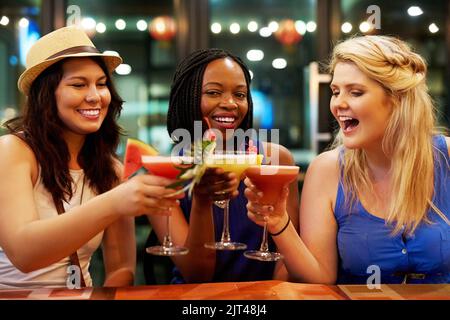 Cheers zu uns. Drei junge Freundinnen toasting in einer Bar. Stockfoto