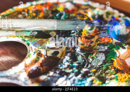 Helle bunte Farben mit Malpinsel, Nahaufnahme. Mehrfarbige Farben auf Palette. Aquarellfarben. Kreatives Hobby. Kunstzeichnung. Stockfoto