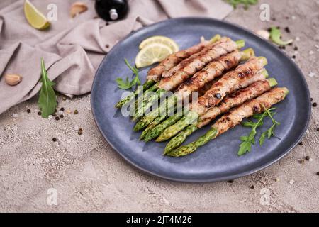 Gesundes Essen - Spargel, eingewickelt mit Speck und Gewürzen auf einem Teller Stockfoto