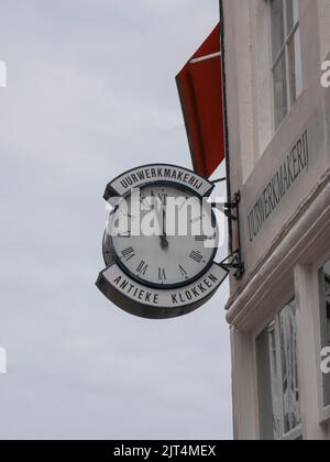 Schild an der Fassade eines Ladens mit Inschrift, Uhrwerk und antiken Uhren Stockfoto