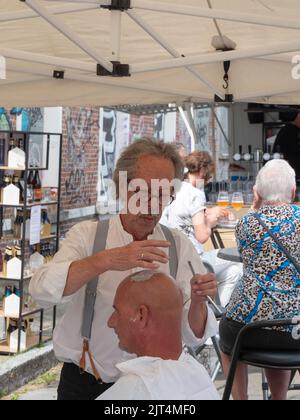 Sint Gillis Waas, Belgien, 21. August 2022, Porträt eines älteren Barbiers, der den Kopf eines Mannes rasiert Stockfoto