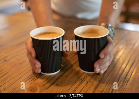 Konzept für Menschen, Getränke und Pflege - Nahaufnahme von Menschenhänden, die in einer Cafeteria Kaffeetassen geben. Stockfoto