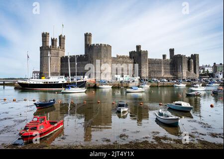 Caernarfon, Großbritannien - 11. Juli 2022: Fischerboote auf dem Fluss Seiont vor dem mittelalterlichen Schloss von Caernarfon in Nordwales Stockfoto