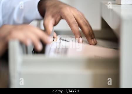 Männliche Hände durchsuchen die Dateien von Unternehmensdokumenten in der Archivschublade. Stockfoto