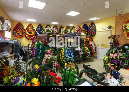 Innenraum des Raumes mit Bestattungszubehör. Geschäft mit Särgen, Beerdigungskränzen und Blumen. Stockfoto