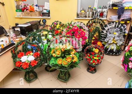 Innenraum des Raumes mit Bestattungszubehör. Geschäft mit Särgen, Beerdigungskränzen und Blumen. Stockfoto