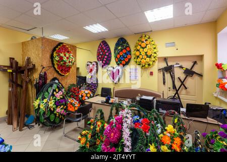 Innenraum des Raumes mit Bestattungszubehör. Geschäft mit Särgen, Beerdigungskränzen und Blumen. Stockfoto