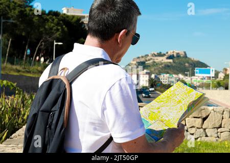Ein älterer kaukasischer Tourist in Brillen mit der Karte von Alicante, Spanien Stockfoto