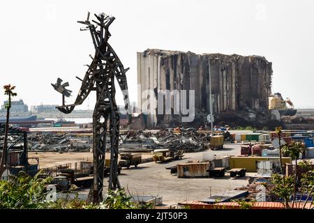 Beirut, Libanon: Vor den zerstörten Getreidesilos steht die Stahlskulptur des Künstlers Nadim Karam, die an die Opfer der tödlichen Explosion vom 4. August 2020 erinnert, die aus dem Schrott der massiven Explosion von 2.750 Tonnen Ammoniumnitrat im Hafen hergestellt wurde. Stockfoto