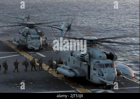 US-Marineinfanteristen, die der Marine Expeditionary Unit (MEU) von 31. zugewiesen wurden, steigen an Bord eines CH-53 Super Henglion Hubschraubers, der am Marine Medium Tiltrotor Squadron (VMM) 265 auf dem Flugdeck des amphibischen Angriffsschiffs 140310 befestigt ist Stockfoto