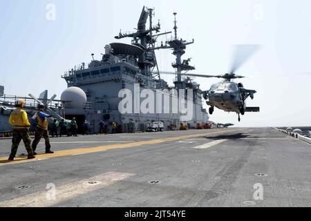 Die Mate 3.-Klasse von US Navy Aviation Boatswain sieht zu, wie der Mate Airman von Aviation Boatswain einen MH-60s Seahawk-Hubschrauber ansteuert, der vom amphibischen Angriff 140411 abheben soll Stockfoto